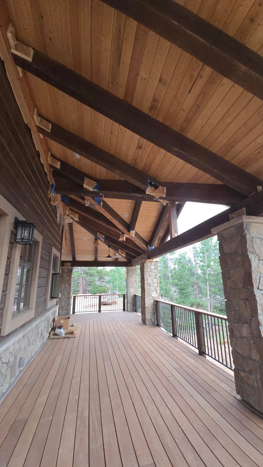 Covered deck with timber beams, stone columns and metal railing near Golden, CO