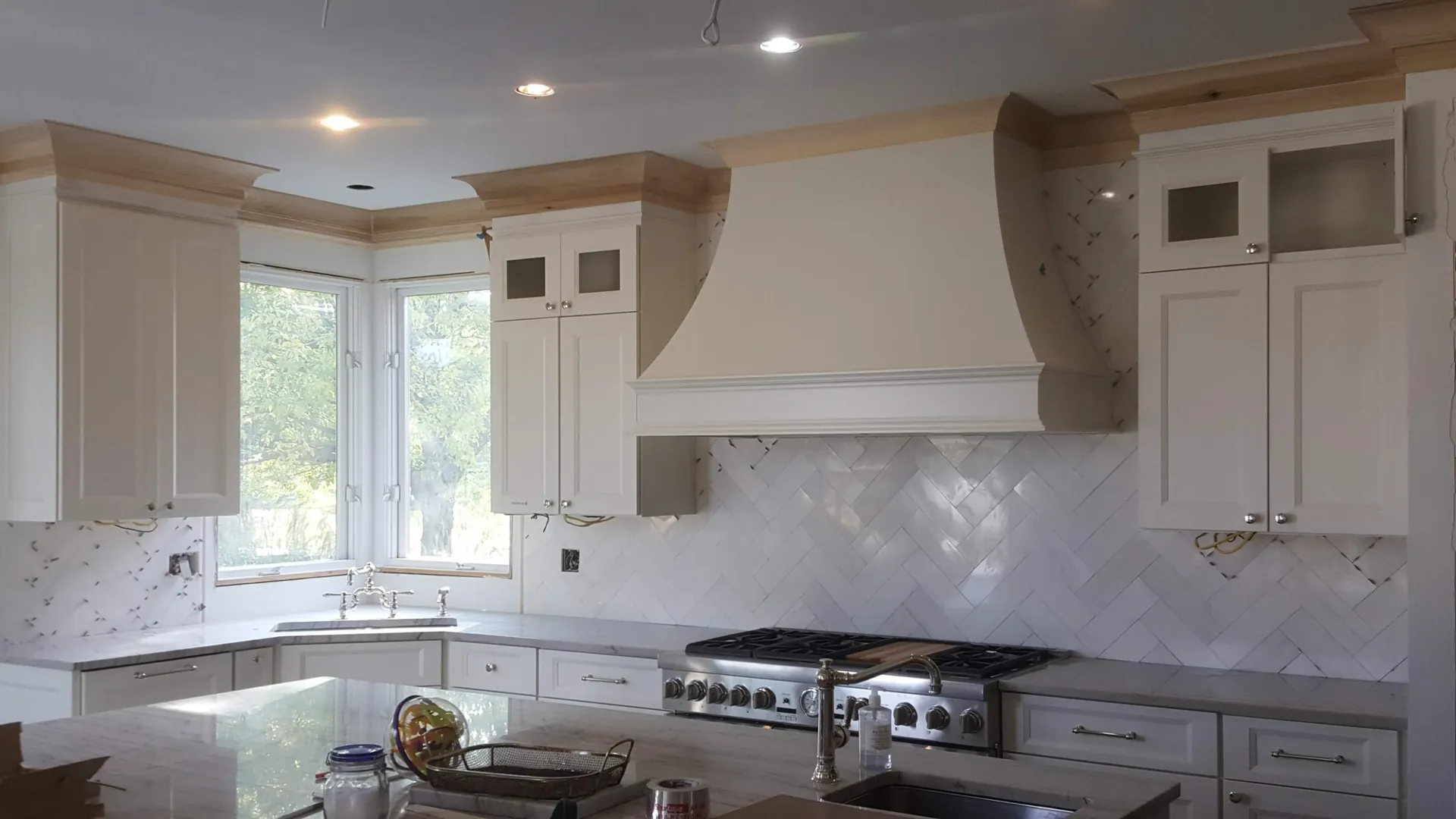 White kitchen cabinets with custom range hood and herringbone backsplash in Golden, CO