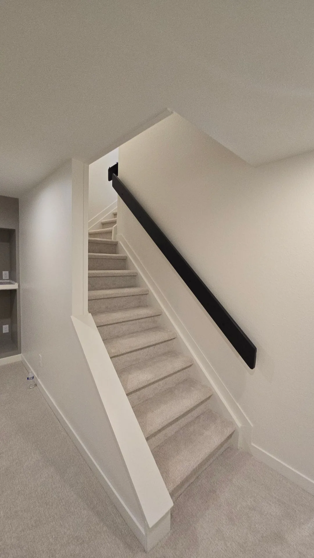 Finished basement stairway with new carpet and black handrail in Golden, CO