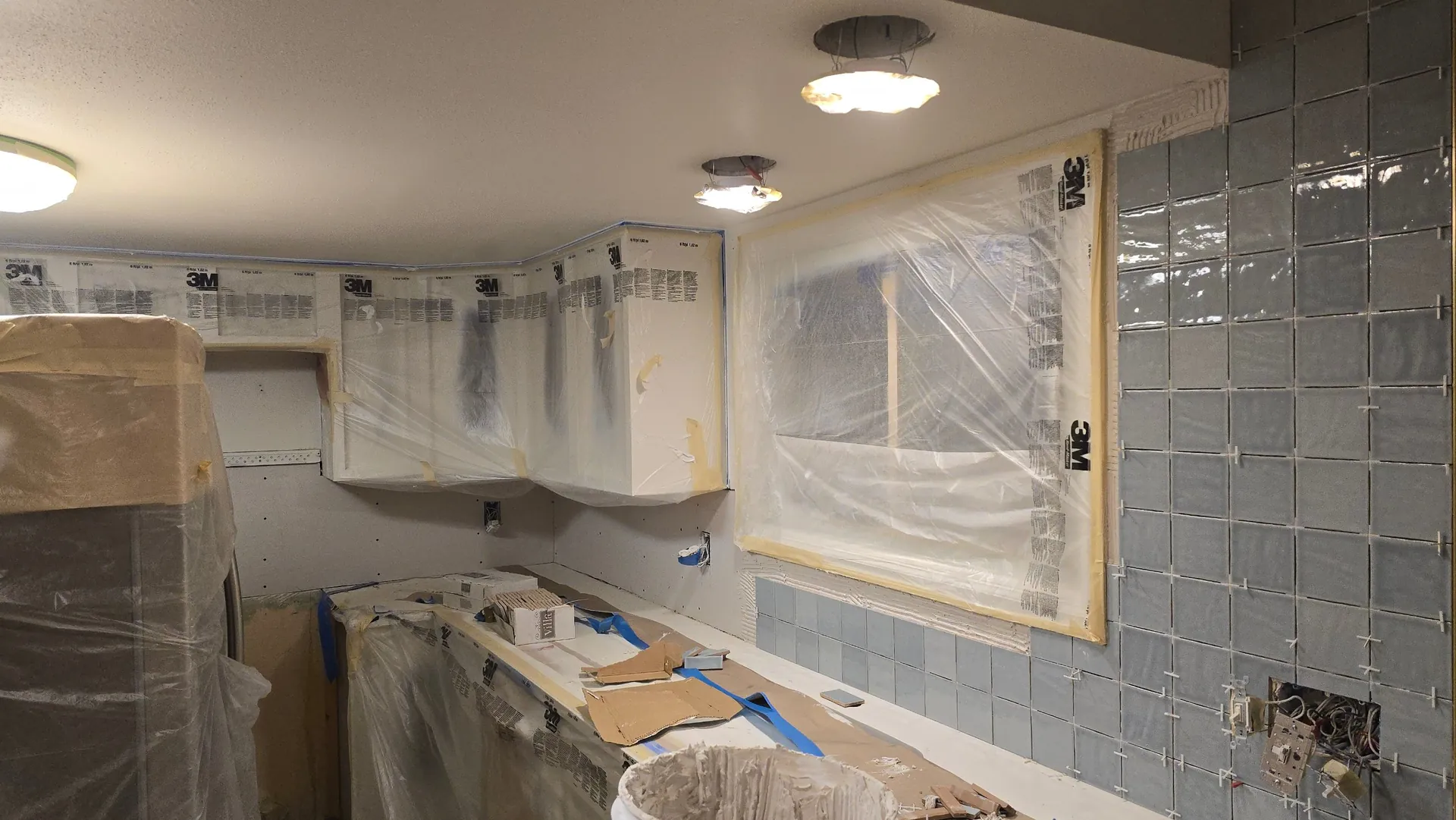 Kitchen masked off for paint while new backsplash tile is set during a remodel in Golden, CO
