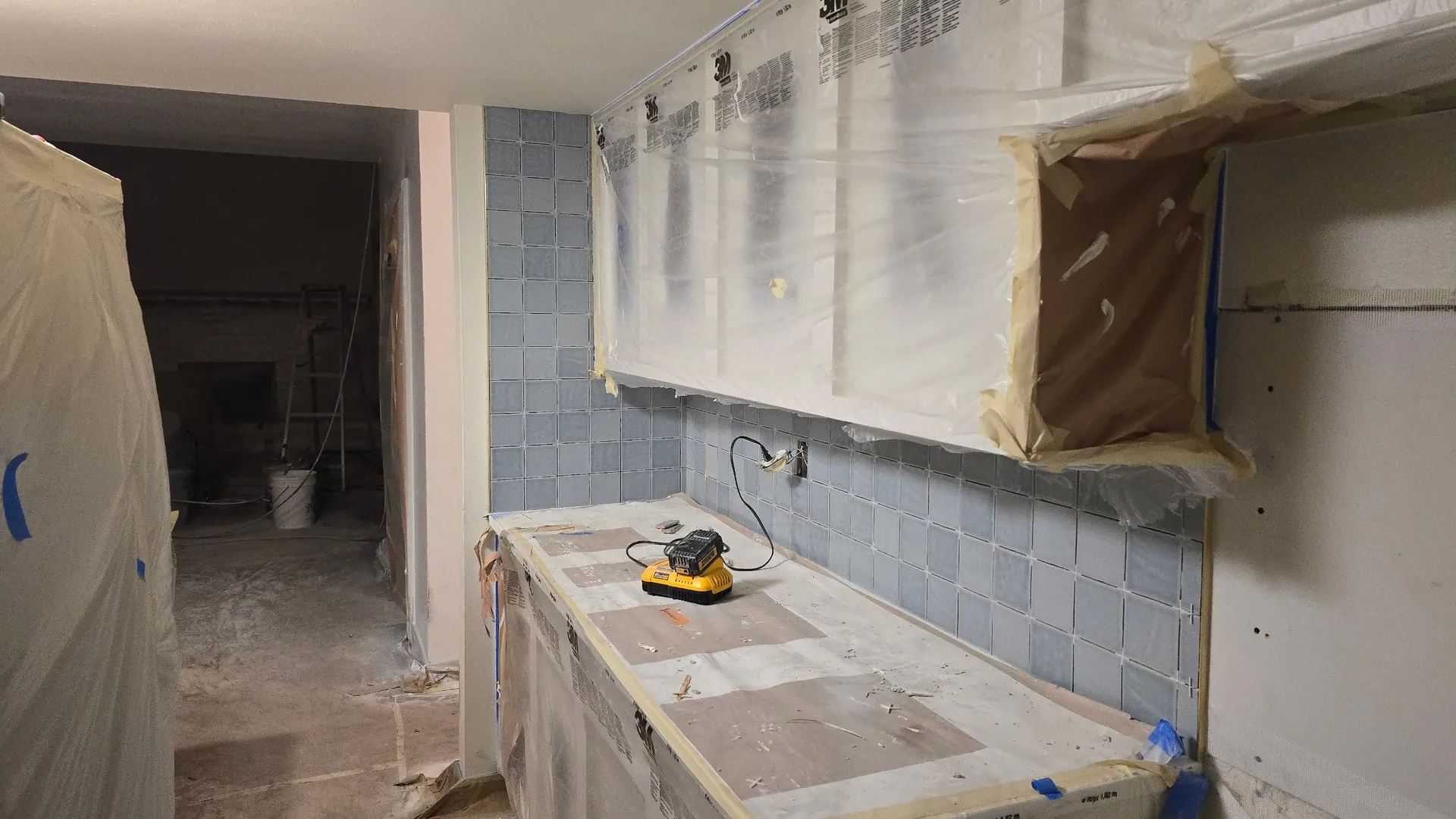 Blue tile backsplash going in with cabinets protected during a kitchen remodel in Golden, CO