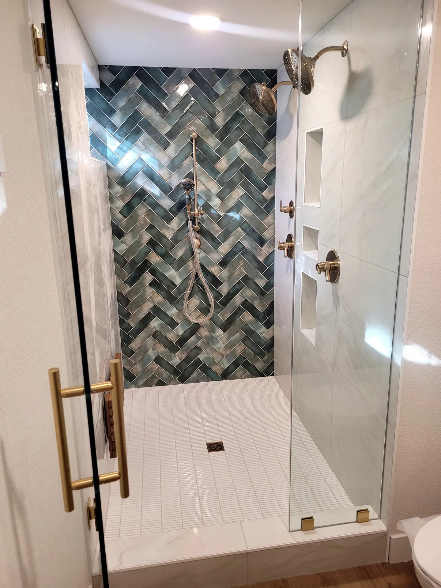 Walk-in shower with herringbone tile and clear glass in a small bathroom in Golden, CO