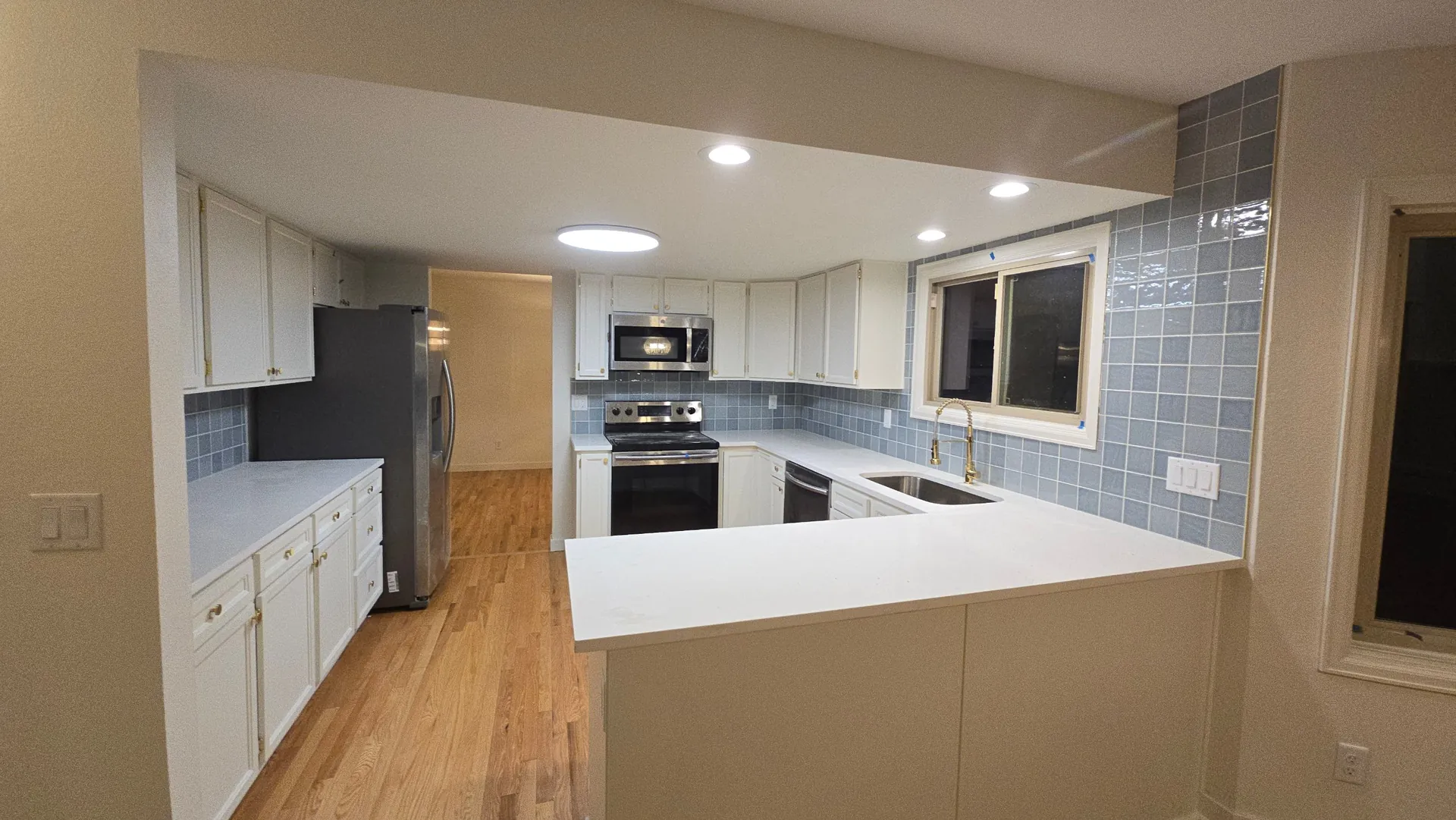 Remodeled kitchen with white cabinets, blue tile backsplash and quartz counters in Golden, CO